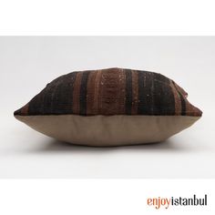 a brown and black striped pillow sitting on top of a white floor