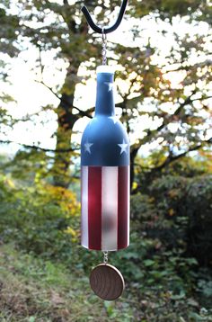 a wind chime with an american flag design hanging from it's side in front of some trees