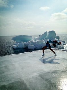 a woman is skating on an ice floet near the water and icebergs