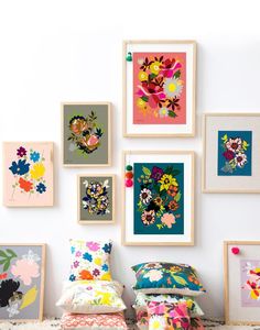 there are many framed pictures on the wall with flowers in them, and one has a pillow