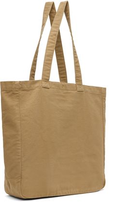 Washed 12 oz organic cotton canvas tote in brown. · Twin shoulder straps · Logo patch at patch pocket · Press-stud closure · Zip pocket at interior · Logo-engraved gold-tone hardware · H15 x W15.75 x D5 / 19.8 L Supplier color: Peanut Brown Cotton Canvas Bag With Pockets, Casual Brown Cotton Canvas Bag, Cotton Canvas Bag With Snap Closure For Daily Use, Daily Use Cotton Canvas Bag With Snap Closure, Brown Cotton Canvas Bag With Adjustable Strap, Casual Cotton Canvas Bag With Flat Pocket, Interior Logo, Carhartt Work In Progress, Press Studs