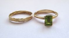 "Stunning set of 2 14K yellow gold stacking rings - a peridot solitaire ring and a unique wedding band. This set consists of 2 beautiful solid gold rings: The 1st is a rustic wedding band, with an uneven design that gives it a distinctive \"handmade\" look. It is forever changing, never looking the same. The 2nd ring has a sparkling green rectangular peridot set in a beautiful base. This can be an awesome engagement ring. This modern bridal ring set is perfect for a boho bride. The rings have a Green Sapphire Ring With Round Band For Wedding, Stackable Peridot Wedding Jewelry, Peridot Ring For Wedding, Green Sapphire Wedding Ring With Round Band, Green Bezel Setting Stackable Rings For Wedding, Green Sapphire Round Band Wedding Ring, Green Stackable Wedding Rings Round Band, Yellow Gold Peridot Rings For Promise, Wedding Stackable Rings In Green With Round Band