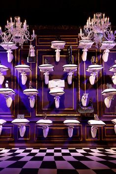 a room filled with lots of white toilets and chandeliers on the wall next to each other