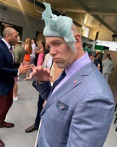 a man in a blue suit and bow tie is standing near other people at an event