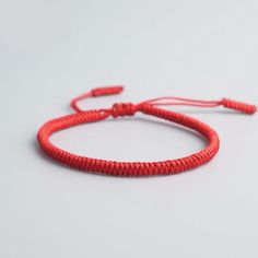 a red string bracelet on a white surface