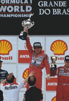 a man holding up a silver trophy on top of a podium with other men around him