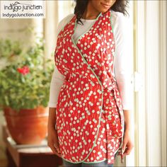 a woman standing in front of a window wearing a red and white floral print scarf