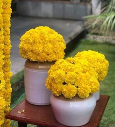 two vases with yellow flowers sitting on a table