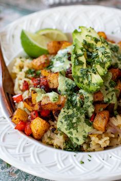 a white plate topped with rice and veggies next to a lime wedge on the side