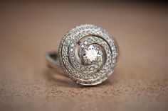 This stunning ring features round cut enhanced diamond with of 0.5 Carat (Color -H Clarity Si1), surrounded with 151 smaller pavé-set round diamonds weighing 0.92 carat (total carat weight 1.42 ct) on a unique swirl ring. The ring is available in 18k white gold or special order. Gold: ----------------- Color- White gold 18K weight- 8.10 g Center stone: ----------------- Type- diamond (Enhanced - treated) Shape- Round Weight- 0.5 ct. color-H clarity- SI1 Side stones: ----------------- total weigh Rings Diamond Unique, Cocktail Rings Diamond, Swirl Diamond Ring, Swirl Engagement Rings, Halo Style Engagement Rings, Swirl Ring, Unique Diamond Rings, Round Cut Engagement Rings, Halo Style