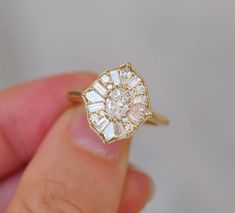 a woman's hand holding a gold ring with an oval shaped diamond in the center