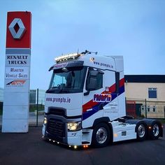 a white truck parked in front of a building with a red, white and blue stripe on it's side