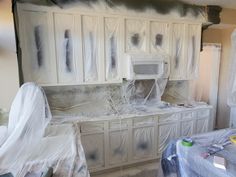 a kitchen with white cabinets covered in plastic