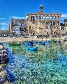 there are many small boats that are in the water near some buildings on the shore