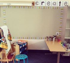 a classroom with desks, chairs and an easel in front of a bulletin board