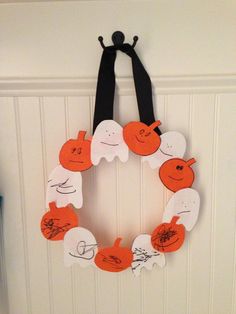 an orange and white wreath hanging on the wall in front of a door with black ribbon