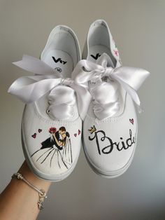 a pair of white wedding shoes with the bride and groom painted on them