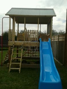 a blue slide in the grass next to a wooden structure