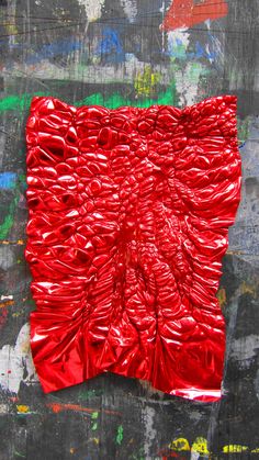 a red piece of art that looks like it is made out of plastic wrappers