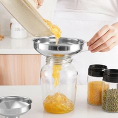 a person pouring mustard into a glass jar