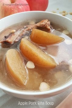 a white bowl filled with soup next to two apples