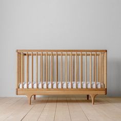 a wooden crib sitting on top of a hard wood floor next to a wall