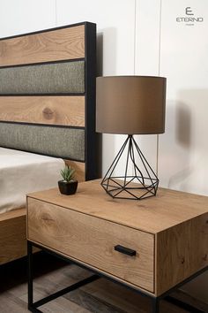 a nightstand with a lamp on top of it next to a bed and night stand