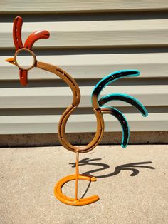 a metal bird sculpture sitting on top of a cement floor next to a garage door