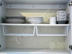 an open refrigerator with dishes and cups on the bottom shelf, labeled soup or soup