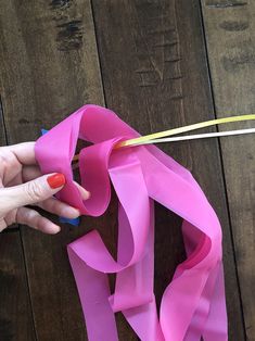 a woman is holding a pink ribbon on a wooden table with scissors and thread in it