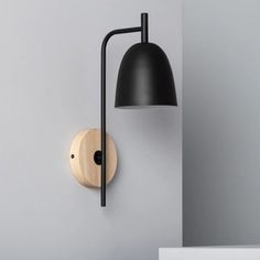 a wall light with a black shade on it and a wooden object next to it