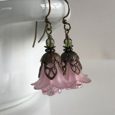 "Pretty in Pink... Add some spring to your wardrobe with these lovely double pink blossoms. Delicate pink petals surround bright pink and white centers. Antique brass filigree caps adorn the tops and a tiny green bead adds a bit of spring pop. These earrings are very lightweight and comfortable to wear. Perfect for a garden wedding, or a gift for a nature lover. And don't forget...Mother's Day is just around the corner. Drop length from bottom of antique brass french earwire: 1\" (25mm) Prefer a Rose Red Flower Earrings For Pierced Ears, Pink Handmade Flower Earrings For Spring, Pink Earrings With Handmade Flowers For Spring, Spring Pink Earrings With Handmade Flowers, Pink Petal-shaped Earrings For Spring, Pink Feminine Dangle Flower Earrings, Pink Feminine Flower Dangle Earrings, Rose Red Flower Earrings, Feminine Pink Dangle Flower Earrings