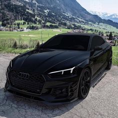 a black car parked in front of a lush green mountain side field with mountains in the background