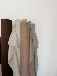 several different colored towels hanging on a white wall next to a brown and tan towel