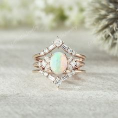 a white opal and diamond ring sitting on top of a table