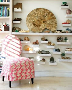 a chair sitting in front of a book shelf filled with lots of books and rocks