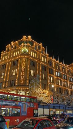 cars and buses are parked in front of a large building with christmas lights on it