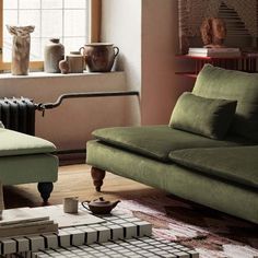 a living room with green couches and vases on the table in front of it