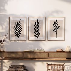 three black and white prints on a wall above a table