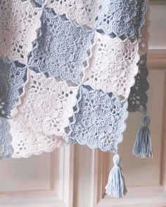 a crocheted blanket with tassels hanging from it's sides in front of a door