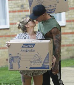 a man and woman kissing while holding boxes on their heads with the box in front of them