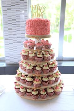 a tiered cake with cupcakes on it