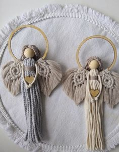 two angel ornaments are hanging on a white doily with tassels and wood beads