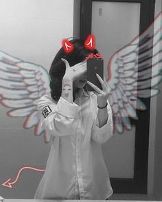 a woman taking a selfie in front of a mirror with angel wings on it