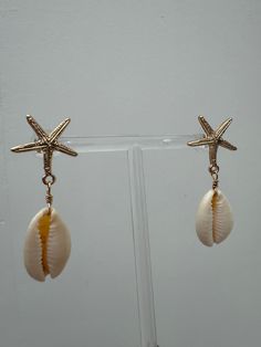 DETAILS:Introducing The Seashell Earrings! These elegant earrings feature seashell charms delicately attached to starfish studs. Add a touch of "beachy charm" to any outfit with these unique earrings! Seashell Earrings, Elegant Earrings, Unique Earrings, Starfish, Gift Guide, Sea Shells, Charms