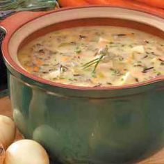 a bowl of soup sitting on top of a wooden table next to onions and garlic