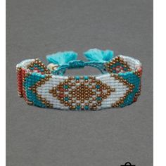 a beaded bracelet with beads and tassels on the end, sitting on a gray surface