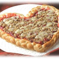 a heart shaped pizza sitting on top of a white plate