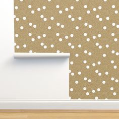 a wall with white dots on it next to a wooden floor and a door frame