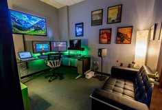 a room with multiple computer monitors and desks on the wall, along with two couches